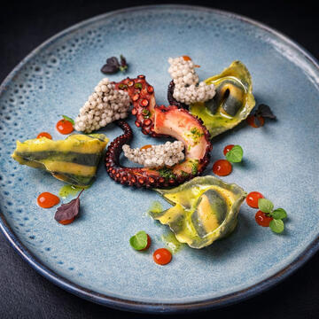 Octopus • Aubergine ravioli • Paprika sauce Fine dining plate with octopus and aubergine ravioli, plated with sauce and garnishes.